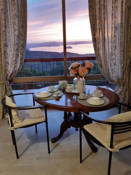 Elegant dining setup at Belvedere del Lago with lake view balcony overlooking Montefiascone, peach roses, and sunset over the