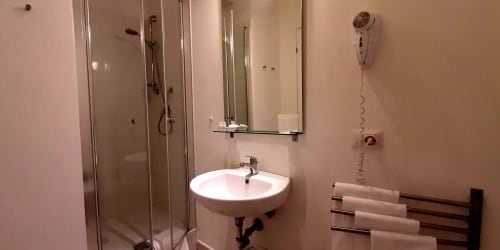 Modern bathroom at Belvedere del Lago with round sink, shower enclosure, heated towel rack, and amenities.