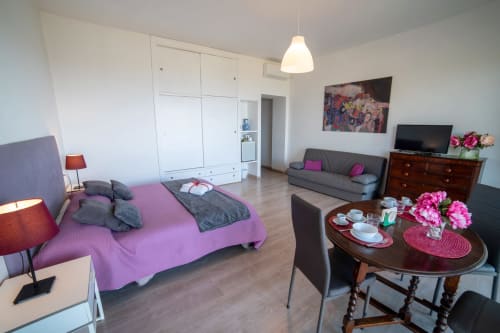 Giglio room at Belvedere del Lago: spacious bedroom with pink bed, gray sofa, dining table with flowers, lake view, modern