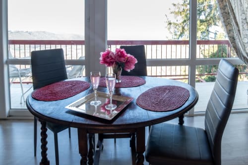 Elegant dining area at Belvedere del Lago with round table, pink peonies, and panoramic lake view from Montefiascone room