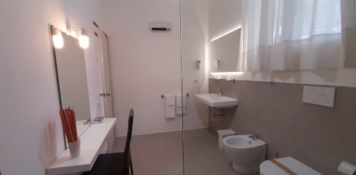 Modern bathroom at Belvedere del Lago with illuminated mirror, sink, bidet, and shower area in Montefiascone