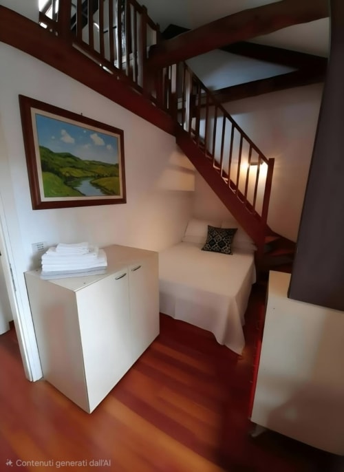 Stanza accogliente alla Mappamondi B&B di Venezia con scala rossa, mobili bianchi, letto e dipinti paesaggistici su pareti rosa.