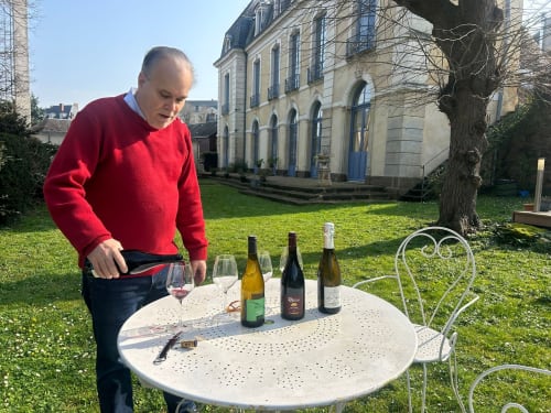 Man pouring wine at Demeure Jousset des Berries in Le Mans with elegant manor house and garden