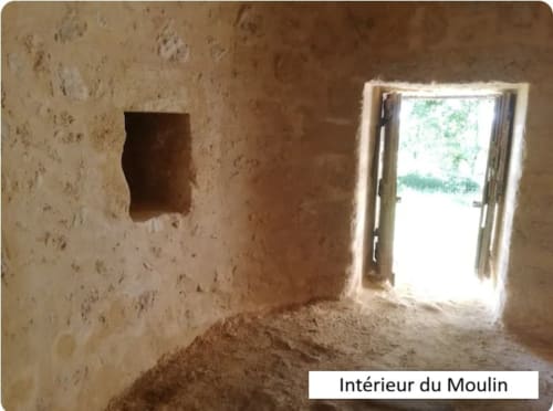 Intérieur du gîte Le Moulin de Bigorre avec murs en pierre rustique, porte donnant sur le jardin et sol sableux à Civrac sur