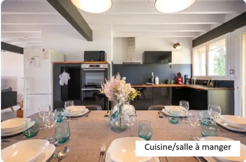 Salle à manger de cottage moderne avec armoires de cuisine noires, table dressée avec fleurs à De Bigorre à Mauvilla, Civrac sur Dordogne