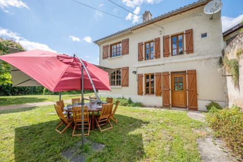 Le jardin champêtre de La Grande Mauvilla avec son parapluie rose et sa table de repas en bois, Civrac-sur-Dordogne