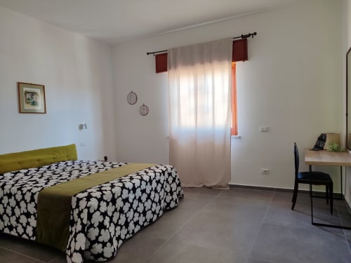 Camera luminosa con letto decorato, scrivania e finestre presso la Mappamondi B&B di Porticello