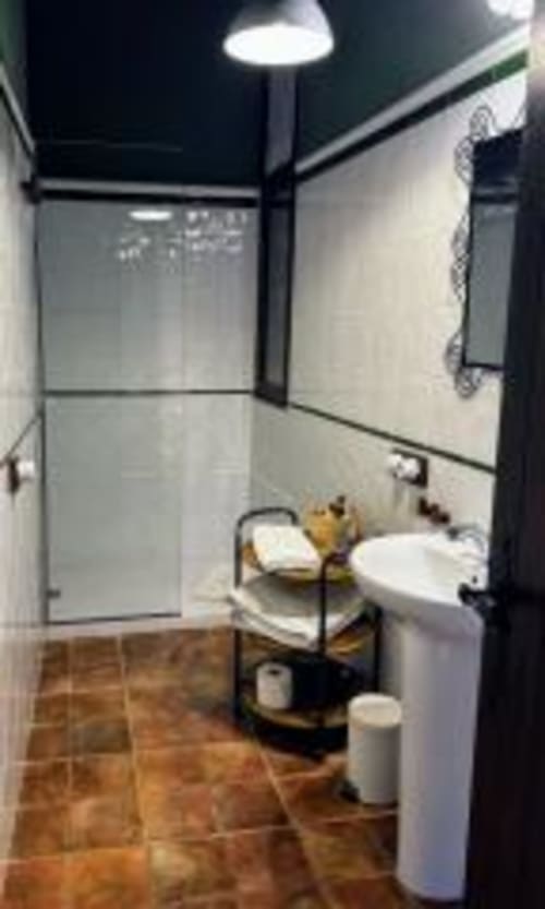 Bany modern a l'apartament Estança La Pau El racó del Bliss amb plat de dutxa, lavabo blanc, vàter i paviment de rajoles