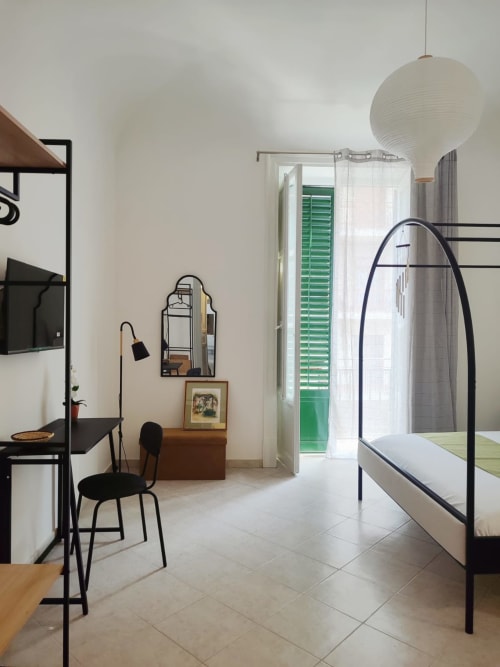 Camera moderna al Mappamondi Venice B&B con letto a struttura metallica nera, arredamento minimalista e persiane verdi
