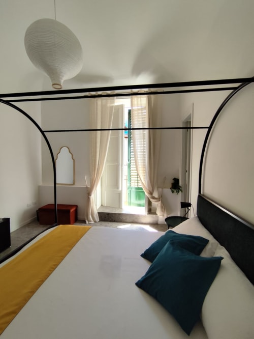 Letto a baldacchino moderno con cuscini turchesi nella luminosa camera Mappamondi Venezia con balcone vista persiane verdi