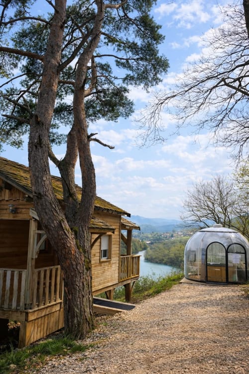 Wooden lodge and bubble pod at Cabanes et lodges du Belvédère overlooking Ain river valley in Serrières-sur-Ain