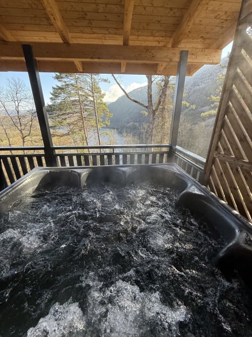 Bain à remous fumant sur la terrasse du gîte dominant un lac de montagne aux Cabanes du Belvédère