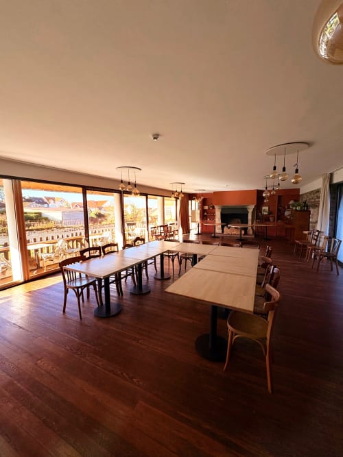 Spacious dining area at Hôtel de la Plage Wissant with wooden tables, pendant lights, and ocean views from large windows