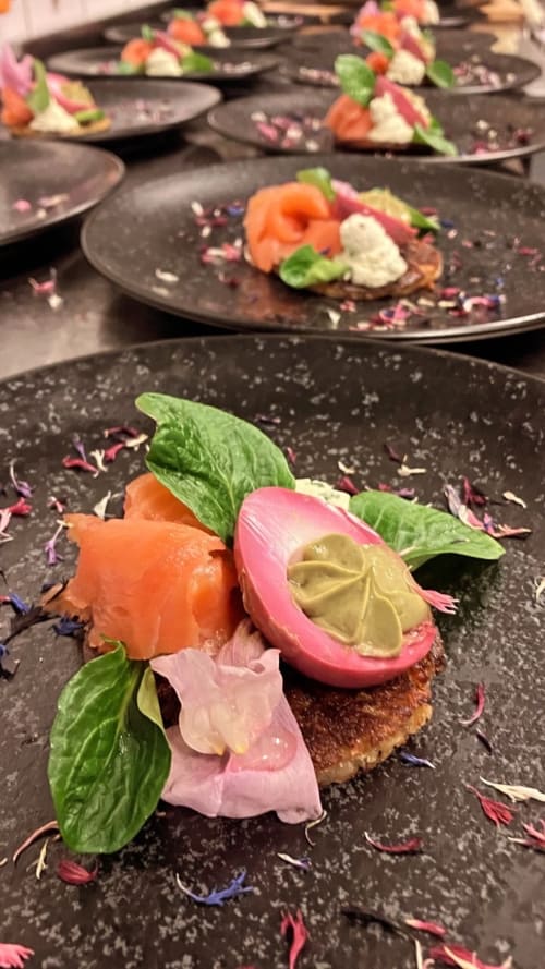 Élégante mise en assiette au Hotel De La Sage : saumon fumé, radis rose, crème de pistache, basilic frais et fleurs comestibles