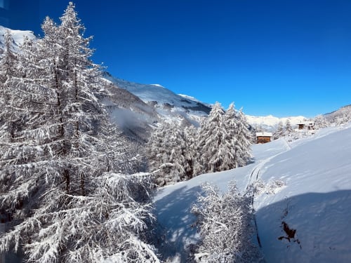 Vallée alpine enneigée avec sapins givrés, montagnes et chalets rustiques à La Sage, Suisse