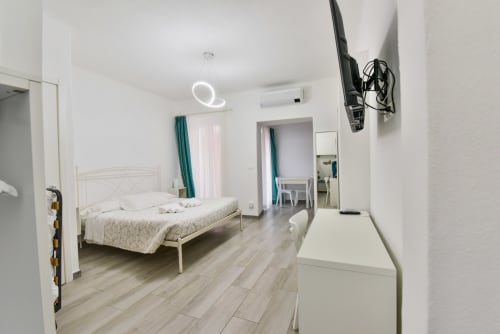 Camera da letto moderna nell'appartamento di Varigotti con letto bianco, pavimenti in legno, lampada neon, climatizzatore e arredi contemporanei