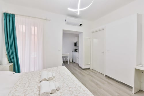 Camera da letto moderna a Varigotti con letto, scrivania, aria condizionata e vista mare attraverso tende turchesi