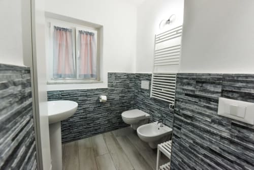Bagno moderno nell'appartamento di Varigotti con piastrelle a righe nere, sanitari bianchi e scaldasalviette
