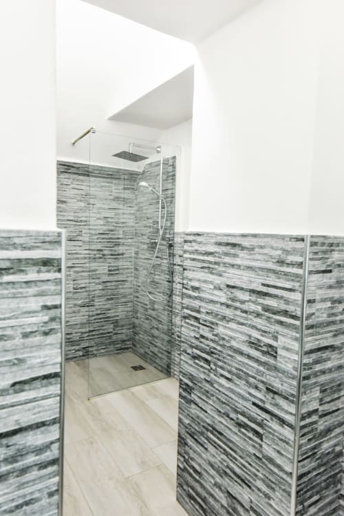 Moderna cabina doccia con piastrelle grigie a righe e porte in vetro nell'appartamento Varigotti, dotata di soffione pioggia