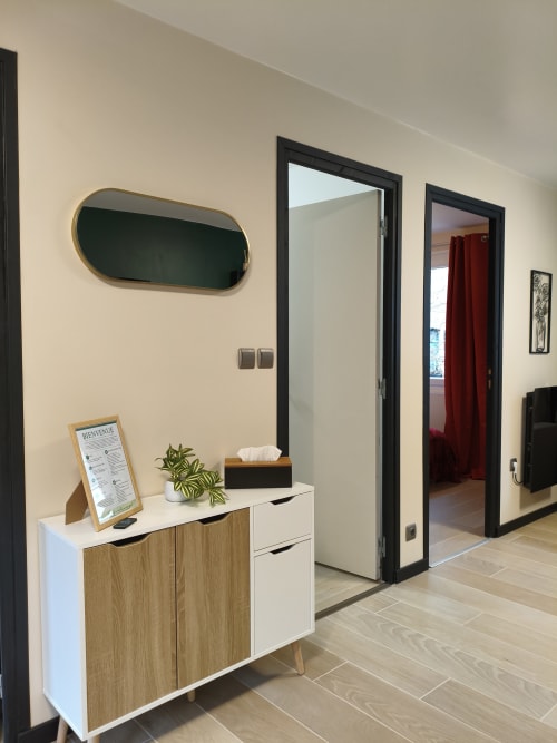 Entrée moderne du Domaine du Vieux Tilleul avec meuble en bois, miroir rond et portes à encadrement noir