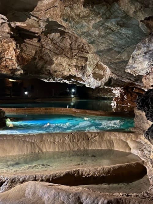Cave in the Dordogne with concretions and illuminated underground water basin