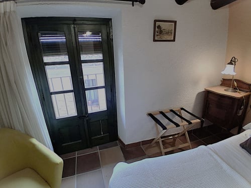 Acogedora habitación rural en RuralGorgs de El Vilosell con cama doble, muebles de madera y puertas francesas hacia la terraza