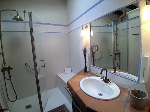 Baño moderno con lavabo ovalado blanco, ducha de cristal y tocador de madera en el rural RuralGorgs de El Vilosell, España