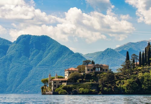 Luxury villa on Lake Como with Alpine mountains, cypress trees, and Italian architecture overlooking the water