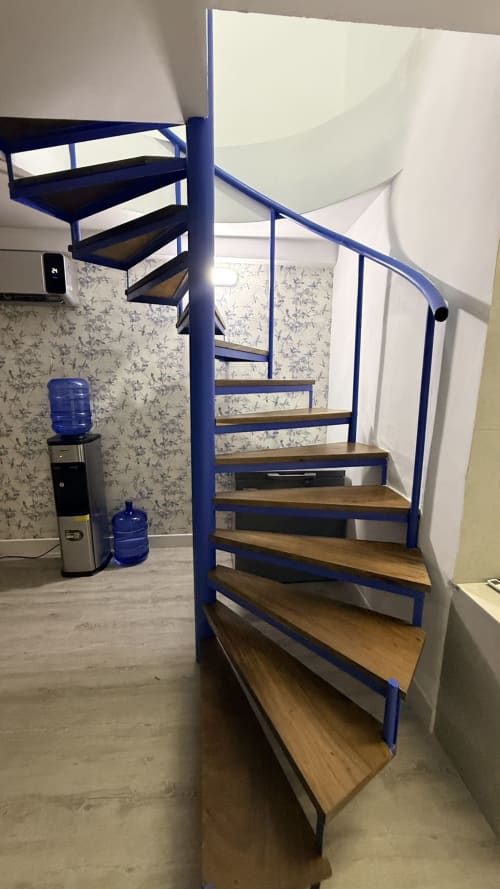 Escalera de caracol azul con peldaños de madera en el apartamento NAUTILUS PALACE del hotel Madrid, con enfriador de agua y papel tapiz floral