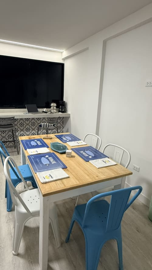 Comedor moderno en apartamento de T-Homes Madrid con mesa de madera, sillas azules y blancas, y amenidades para huéspedes