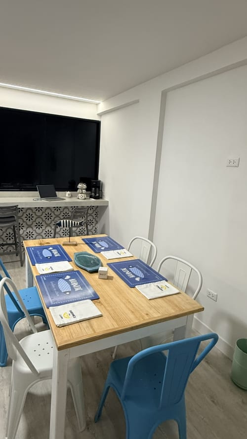 Zona de comedor moderna en T-Homes Nautilus Palace, apartamento de Madrid con mesa de madera, sillas azules y blancas, y área de trabajo.
