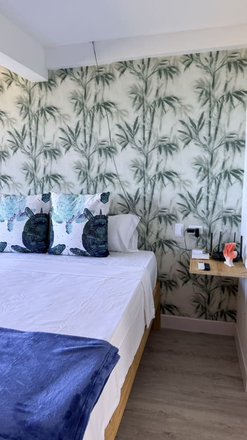 Dormitorio del Palacio Nautilus en Madrid con papel tapiz de bambú, cama blanca, almohadas de tortuga, mesita de noche de madera y comodidades modernas