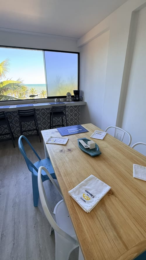 Comedor del apartamento Nautilus Palace con vista al mar en Madrid, mesa de madera, sillas azules, ventanal frente al mar