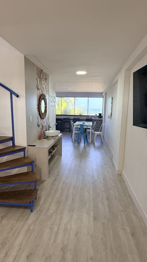 Moderno pasillo del apartamento en T-Homes Nautilus Palace de Madrid con vistas al mar, hacia zonas de comedor y trabajo con escalera azul