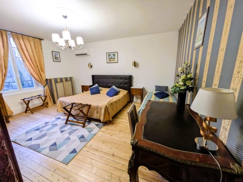 Élégante chambre du Château de Quesmy avec lit king-size, papier peint rayé, parquet et vue sur le jardin