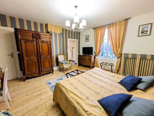 Chambre élégante au Château de Quesmy avec papier peint rayé, armoire ancienne et vue sur le jardin