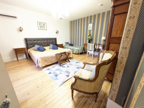 Chambre Azur du Château de Quesmy avec papier peint rayé, mobilier en bois et vue sur le jardin