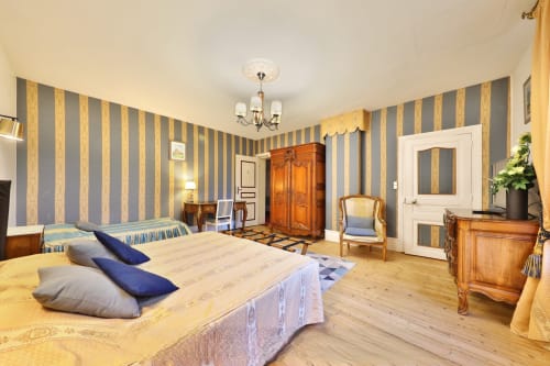 Chambre Azur du Château de Quesmy, avec murs rayés bleu et or et mobilier en bois