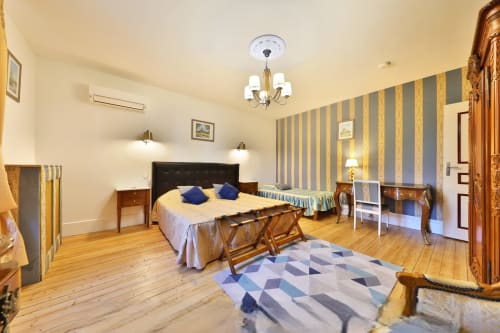 Chambre spacieuse au Château de Quesmy avec papier peint rayé, lit en bois, accents bleus et vue sur le jardin à Quesmy, France