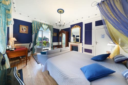 Chambre de luxe au Château de Quesmy aux murs bleus, lit à baldaquin, balcon vue jardin et mobilier d'époque