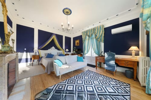 Chambre Saphir du Château de Quesmy : élégante chambre aux murs bleu marine, lit à baldaquin bleu, rideaux turquoise et vue sur le jardin