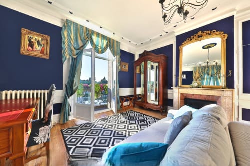 Chambre Saphir du Château de Quesmy avec murs bleu marine, mobilier élégant, miroir ouvragé et vue sur le jardin de balcon.