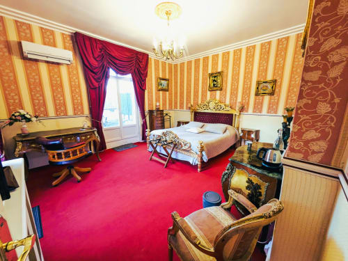Chambre Rubis luxueuse du Château de Quesmy avec moquette rouge, papier peint rayé et mobilier élégant