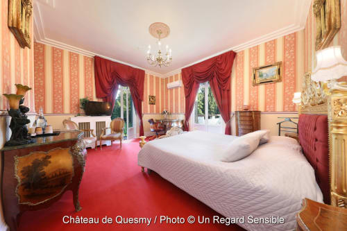 Luxueuse Chambre Rubis au Château de Quesmy avec murs rayés rouges, lustre et vue sur le jardin