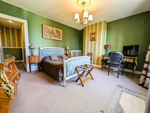 Elegant Chambre Emeraude at Chateau de Quesmy with green damask walls, white metal bed frame, and garden view.