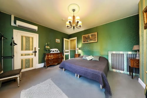 Emeraude bedroom at Chateau de Quesmy with green walls, queen bed, and garden view