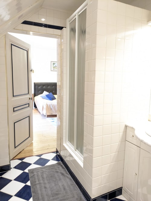 Salle de bain moderne du Château de Quesmy avec carrelage crème, douche vitrée et vue sur la chambre