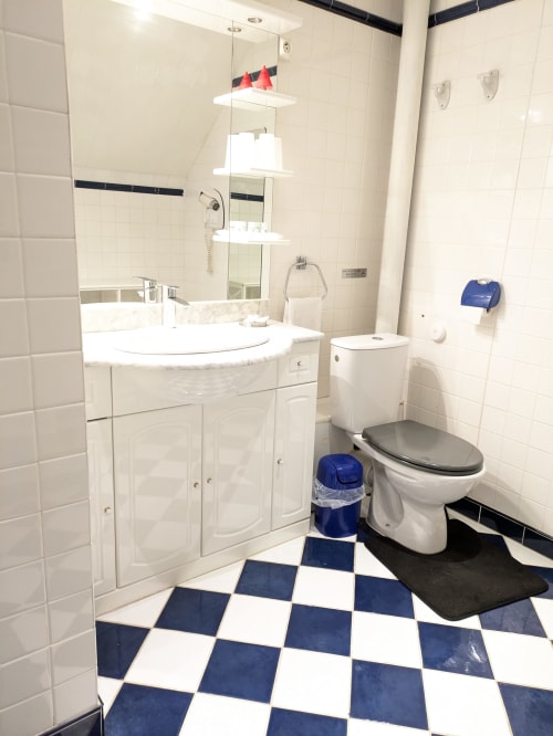 Salle de bain moderne de la Chambre Azur au Château de Quesmy avec vasque blanche, toilettes et carrelage géométrique bleu et blanc