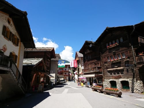 Traditional Alpine village street in La Sage with wooden chalets, Hotel De La Sage nestled among historic buildings under