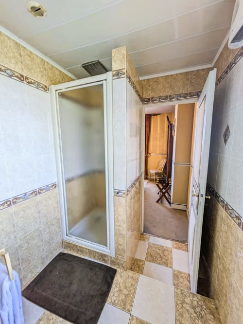 Salle de bain moderne avec douche spacieuse, carrelage beige et plafond blanc au Château de Quesmy, Quesmy France